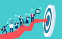 Businesspeople working on top of a red arrow as it approaches its goal