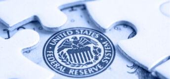 Image of a white puzzle, with a piece revealing the logo for the US Federal Reserve System.