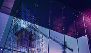 KRE Capital Management debuts with $425m fund and $1bn-plus lending capacity Construction crane and a new high rise building reflected into a newly built office building. New offices are being built to satisfy the growing demand