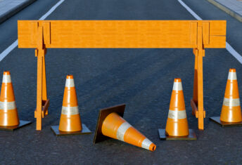 Under construction traffic cones and orange barrier road boundary.