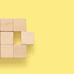 Brookfield moves to acquire remaining stake in Oaktree Merger abstract. Group of wooden cube block on yellow background with copy space