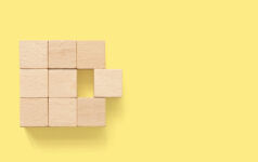 Brookfield moves to acquire remaining stake in Oaktree Merger abstract. Group of wooden cube block on yellow background with copy space