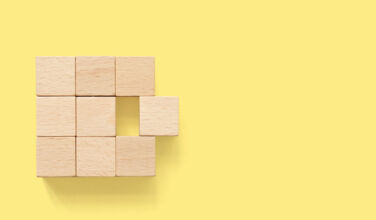 Merger abstract. Group of wooden cube block on yellow background with copy space