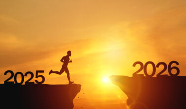 New Year 2026, Inspiration and progress towards new success. Silhouettes of human jumping over cliff towards finish line with text new year 2026 on sunset beautiful