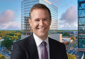 Peter Gordon, head and chief investment officer, US commercial real estate debt, at AllianceBernstein in front of an image of 110 East Boulevard in Charlotte, North Carolina.