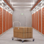 Self Storage Units And Close-up Of Hand Truck With Cardboard Boxes In Corridor