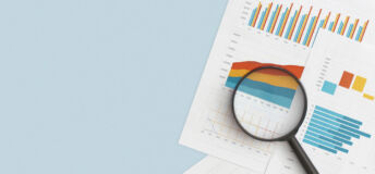 Business graphs, charts and magnifying glass on table