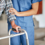 Shot of a woman assisting her elderly patient who's using a walker for support
