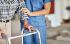 Shot of a woman assisting her elderly patient who's using a walker for support