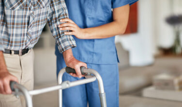 Shot of a woman assisting her elderly patient who's using a walker for support