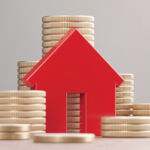 Image of a block house next to stacks of coins.