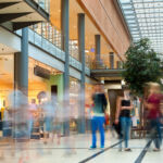 Brookfield secures $800m CMBS refi for Oakbrook Center Generic shopping mall with many unrecognizable blurred people buying sales goods in various boutiques and shops.
